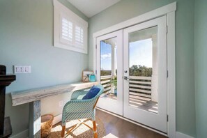 Ein Balkon mit Korbstuhl, einem kleinen Tisch und Blick ins Freie.