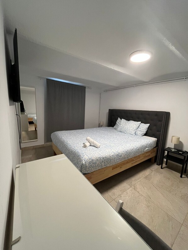 A bedroom with a bed, a bedside table, a lamp, a mirror, and a ceiling light. - N1 Casa de Madrid (Madrid)