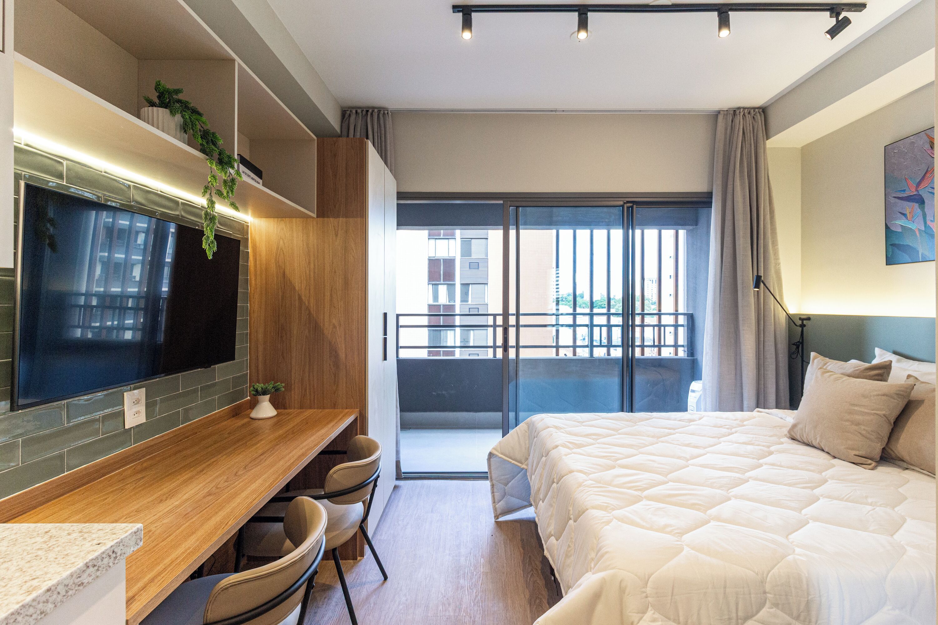 Une chambre d’hôtel moderne dotée d’un grand lit, d’un bureau avec une chaise, d’une télévision et d’un balcon offrant une vue sur la ville.