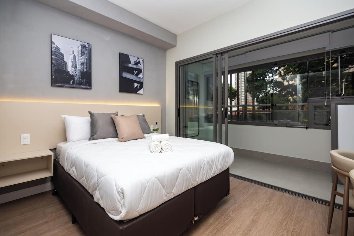 Un dormitorio moderno con una cama grande, un escritorio y vistas al exterior.