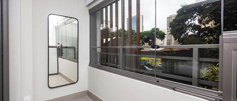 Una habitación moderna con un ventanal grande, un espejo montado en la pared y un piso limpio con baldosas.