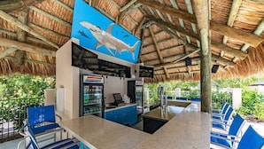 A restaurant with a thatched roof, blue chairs, and a large shark mural on the wall. - Accessible 2BR Pool-View Family Suite in Naples (Naples)