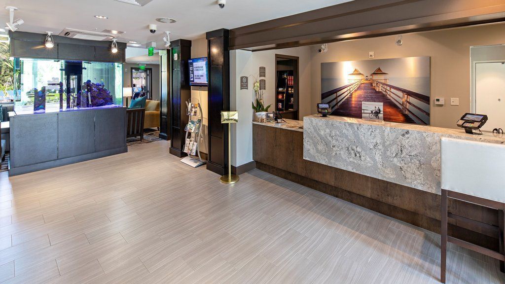 A modern reception area with a marble counter, a reception desk, and a digital screen.