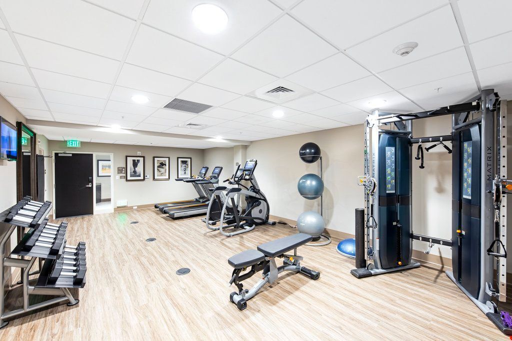 A gym with cardio machines, weightlifting equipment, and a bench.