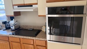 Una cucina con forno a incasso, piano cottura e macchina per il caffè.