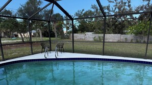 Una piscina trasparente con due sedie e una struttura in metallo.