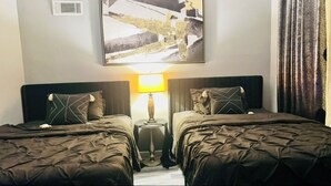 Ein Hotelzimmer mit zwei Betten, einem Nachttisch mit Lampe und einem großen, abstrakten Gemälde an der Wand.