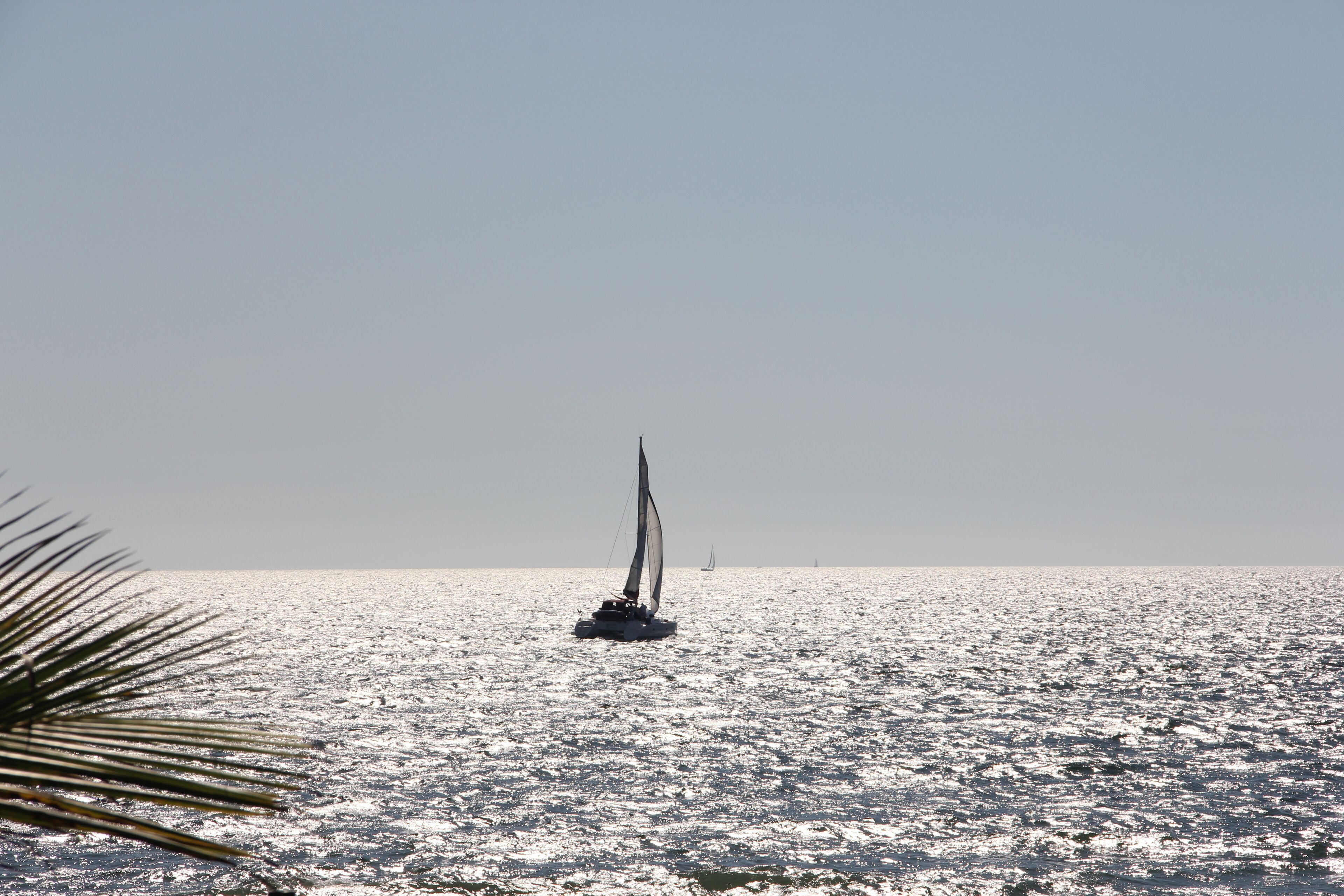 Un velero sobre aguas tranquilas bajo un cielo despejado.