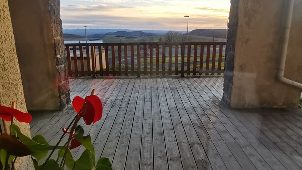 Una terraza de madera con vistas a un paisaje a través de un arco.