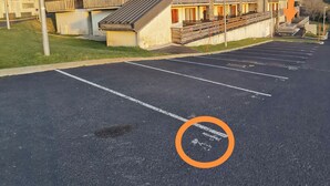 Un edificio de varios pisos con balcones y un estacionamiento frente a él.