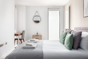 Une chambre d’hôtel comprenant un lit, un bureau, une chaise, une commode et un miroir.