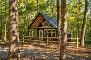 Eine Hütte mit schrägem Dach, einer Holzterrasse und einem eingezäunten Bereich.