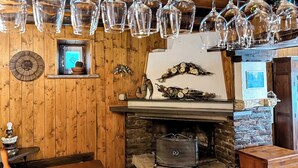 A rustic interior with a stone fireplace, wooden walls, and a hanging light fixture.