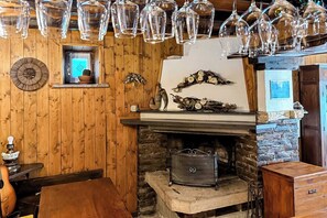 A rustic interior with a stone fireplace, wooden walls, and a hanging light fixture. - Villa al Lago - Where the Dolomites meet Lake Santa Croce (Lizzona)