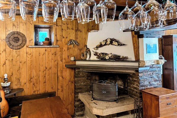 Un intérieur rustique avec une cheminée en pierre, des murs en bois et un luminaire suspendu.