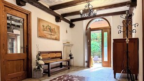 A hallway with a wooden bench, a chandelier, and a door leading outside.