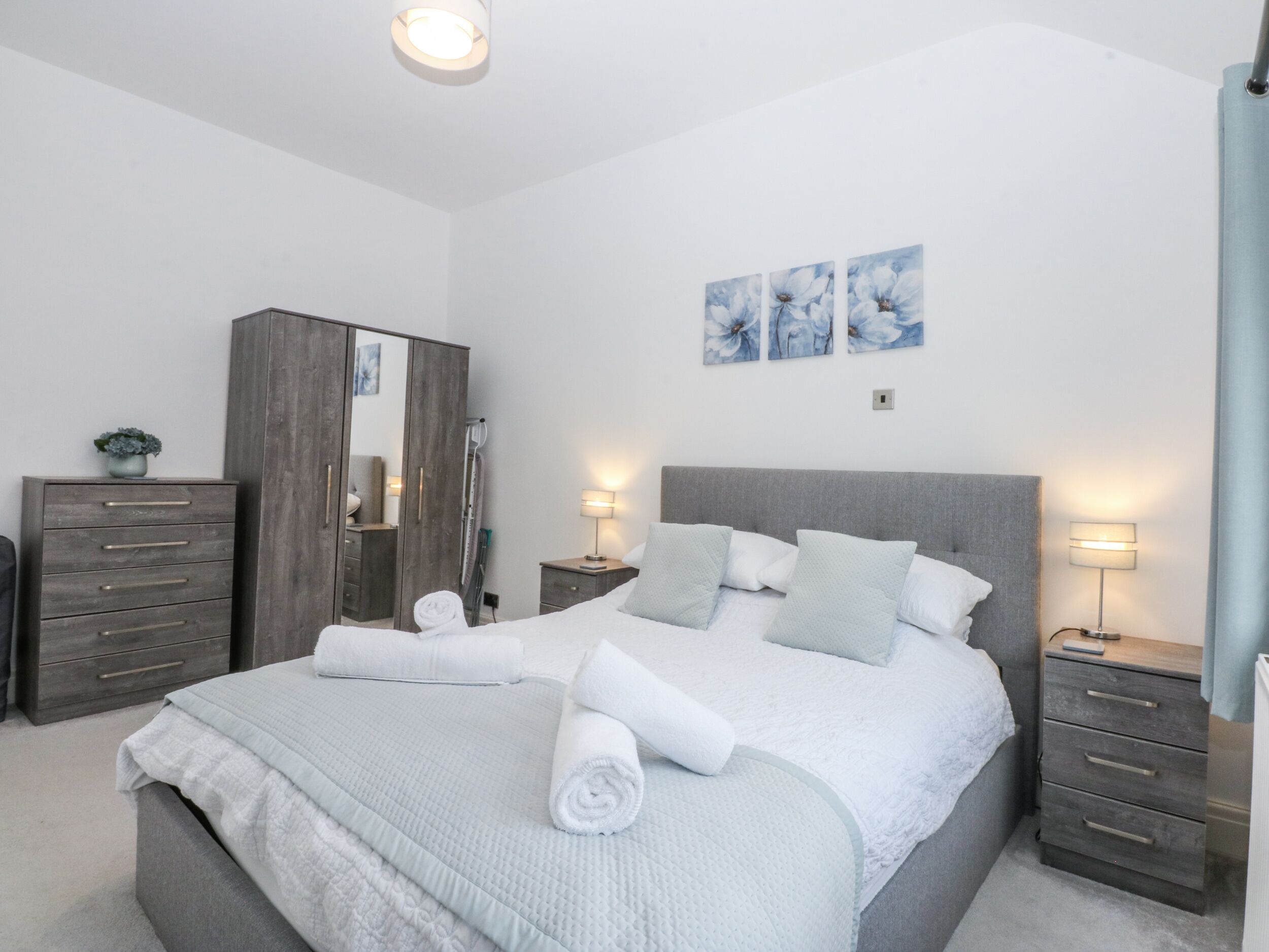 A modern bedroom with a large bed, a wardrobe, and a nightstand.