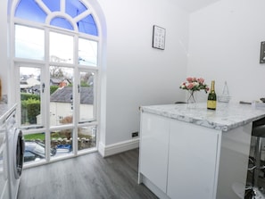 A kitchen with a large window, white cabinets, and a marble countertop. - Capel Y Ffynnon (Llandudno Junction)