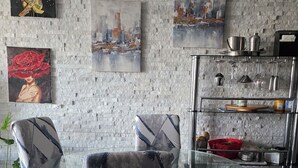 Een moderne keuken met een achterwand van steen, een glazen eettafel en moderne stoelen.