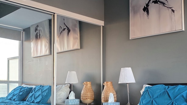 Een moderne slaapkamer met een groot bed, een spiegel en kunstwerken aan de muur.