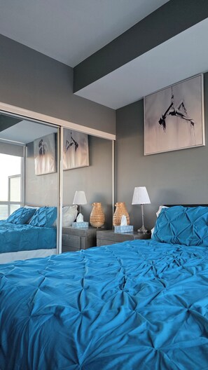 Une chambre à coucher moderne avec un grand lit, un miroir et des œuvres d’art accrochées aux murs.