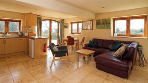 A spacious living area with a sofa, chairs, a dining table, and a kitchen area with a sink and cabinets. - Brush and Boot (York)