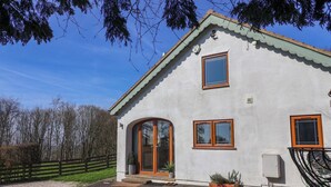 A two-story building with a white exterior, a green roof, and a wooden door. - Brush and Boot (York)