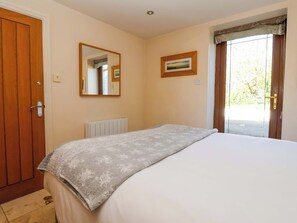 A bedroom with a bed, a wooden door, a radiator, a mirror, and a window with curtains. - Brush and Boot (York)