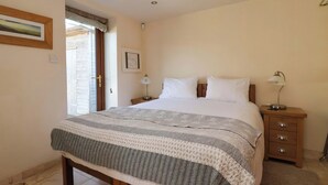 A bedroom with a bed, bedside tables, a nightstand, a door, and a wall-mounted picture. - Brush and Boot (York)