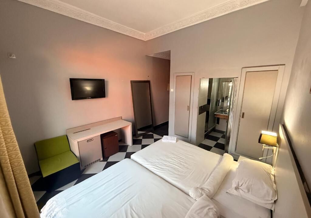 A hotel room with a bed, a desk, a television, and a mirror.