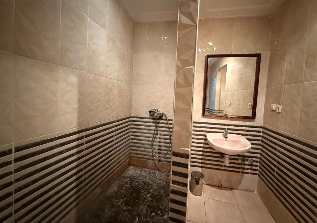 A bathroom with a marble floor, a sink, and a shower.