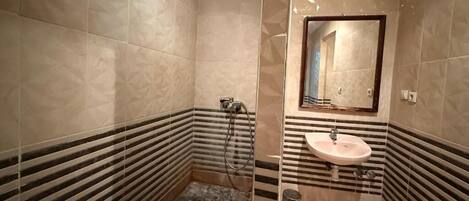 A bathroom with a marble floor, a sink, and a shower.