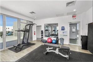 A gym with exercise equipment, a bench, and a mirror. - The Azure Grand Penthouse I Private Hot Tub & Views (oranjestad)