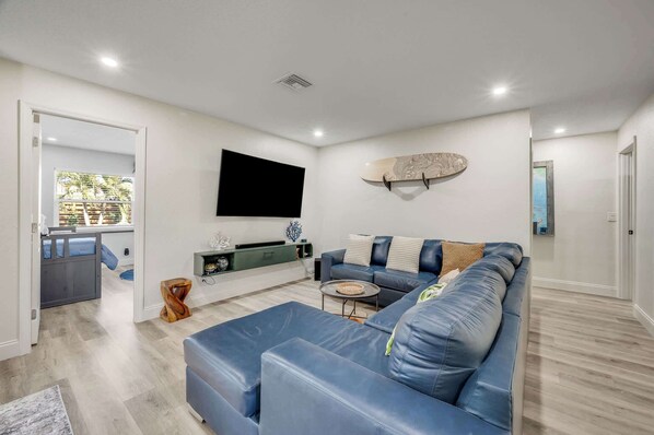 Una sala de estar moderna con un sofá azul, un televisor de pantalla plana en la pared y un monopatín.