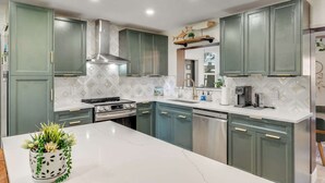 A modern kitchen with green cabinets, a white countertop, and a stainless steel range hood. - Canal Side Cocoa Beach 3BR 3BA Retreat (Cocoa Beach)