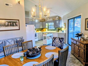 A modern kitchen with a dining area, featuring a chandelier, a refrigerator, and a dining table with chairs. - Alpine Cottage Getaway in Dillard GA- Pet Friendly! (Dillard)