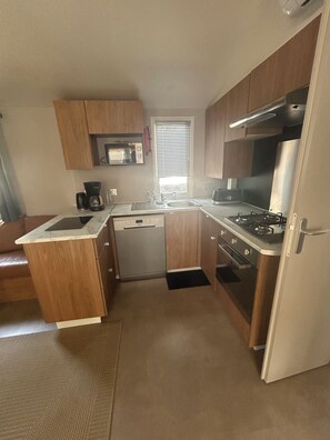 A compact kitchen with wooden cabinets, a built-in microwave, a gas stove, and a dishwasher.