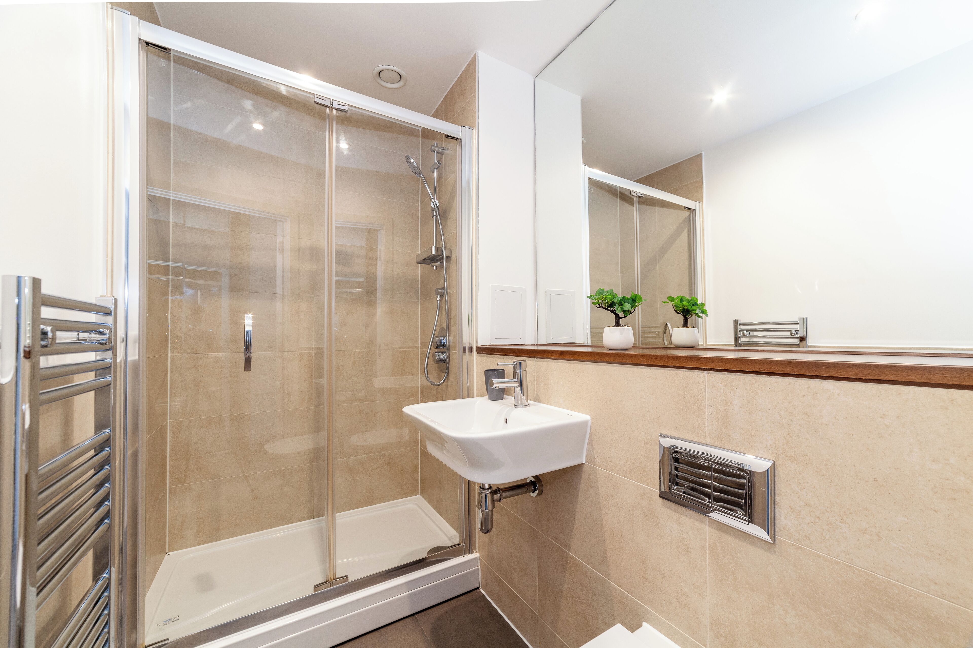 Une salle de bain moderne avec une douche à parois de verre, un lavabo blanc et un miroir au-dessus du lavabo.