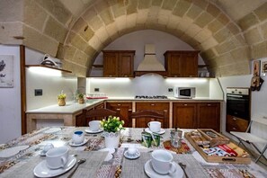 Uma cozinha com teto de pedra em arco, armários de madeira, fogão a gás, micro-ondas e forno.