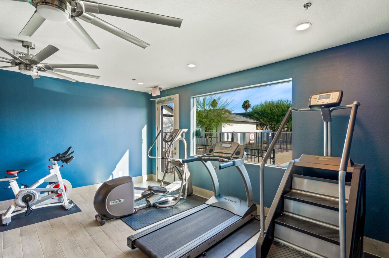 A gym with a treadmill, stationary bike, elliptical, and stair climber.