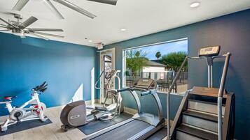 A gym with a treadmill, stationary bike, elliptical, and stair climber.