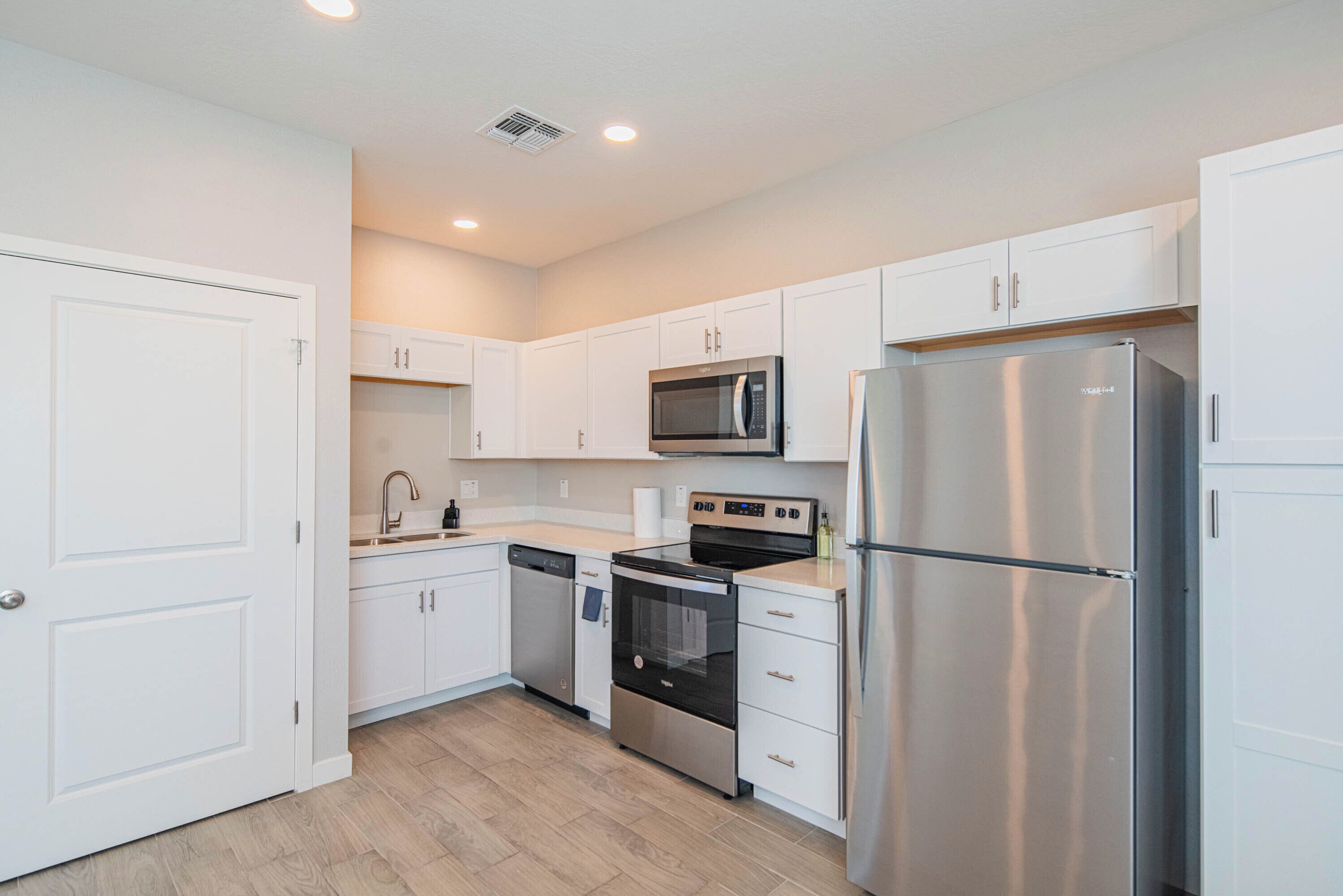 A modern kitchen with white cabinetry, stainless steel appliances, and a wooden countertop.