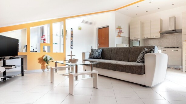 Ein modernes Wohnzimmer mit Sofa, Couchtisch und Fernseher.