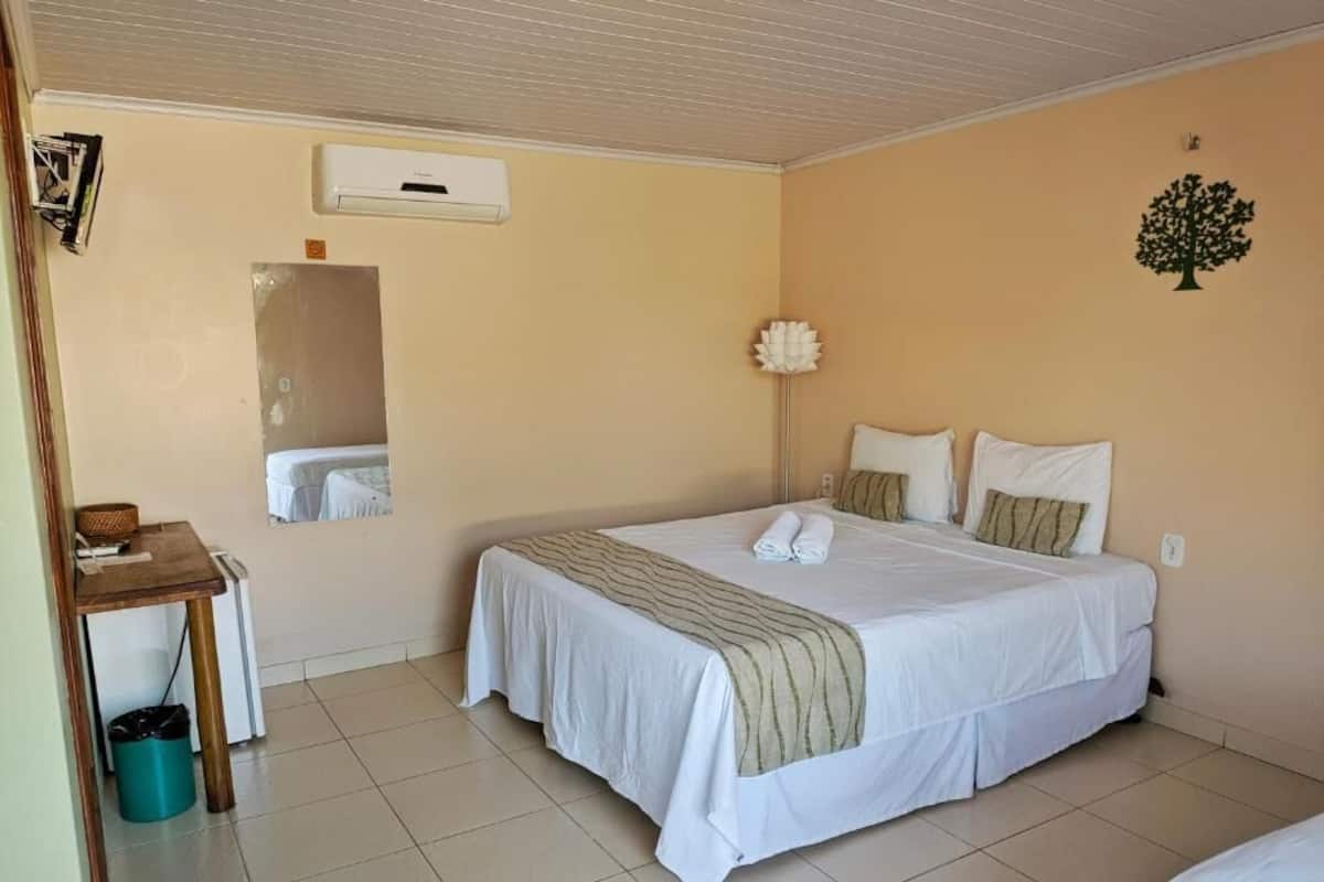 Une chambre à coucher comprenant un lit, une table de chevet, une lampe et un climatiseur fixé au mur.