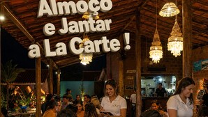 Un ristorante con posti a sedere all'aperto, travi in legno e luci a sospensione.