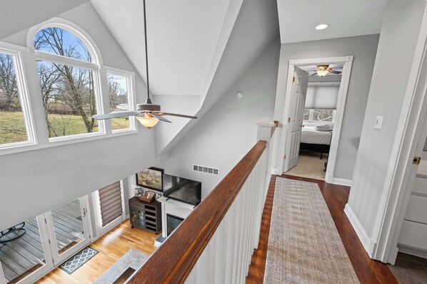 A spacious loft bedroom with a large skylight, a fireplace, and a view of the outdoors. - Country Home with Hot Tub, Fire Pit, for 10 Guests! (Florence)