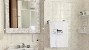 Un baño con lavamanos, espejo, toallero y un diseño decorativo de azulejos.