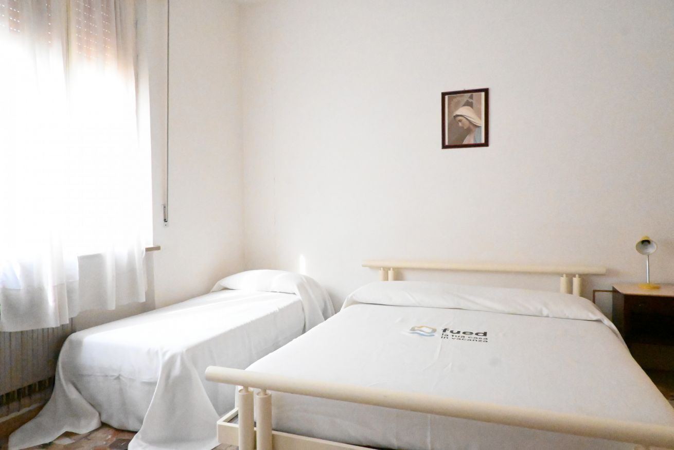 Ein Zimmer mit zwei Betten, einem kleinen Tisch und einem Bild an der Wand.