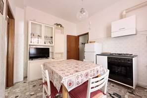 Una cucina con tavolo da pranzo, mobili, televisione e piano cottura.
