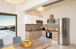 Una cocina moderna con un refrigerador grande, armarios de madera y una zona de comedor con una mesa y sillas.